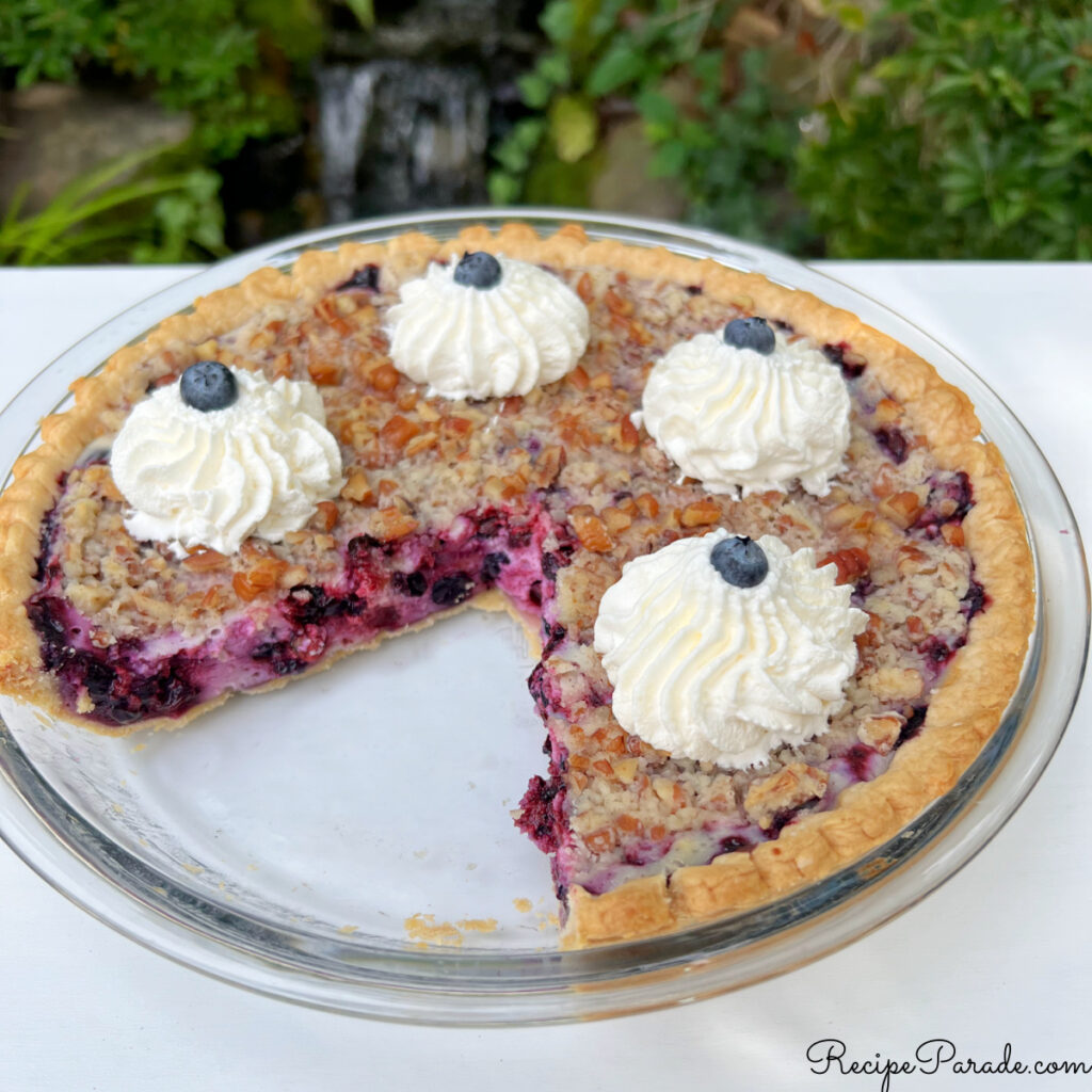 Blueberry Pie, sliced, and topped with whipped cream.