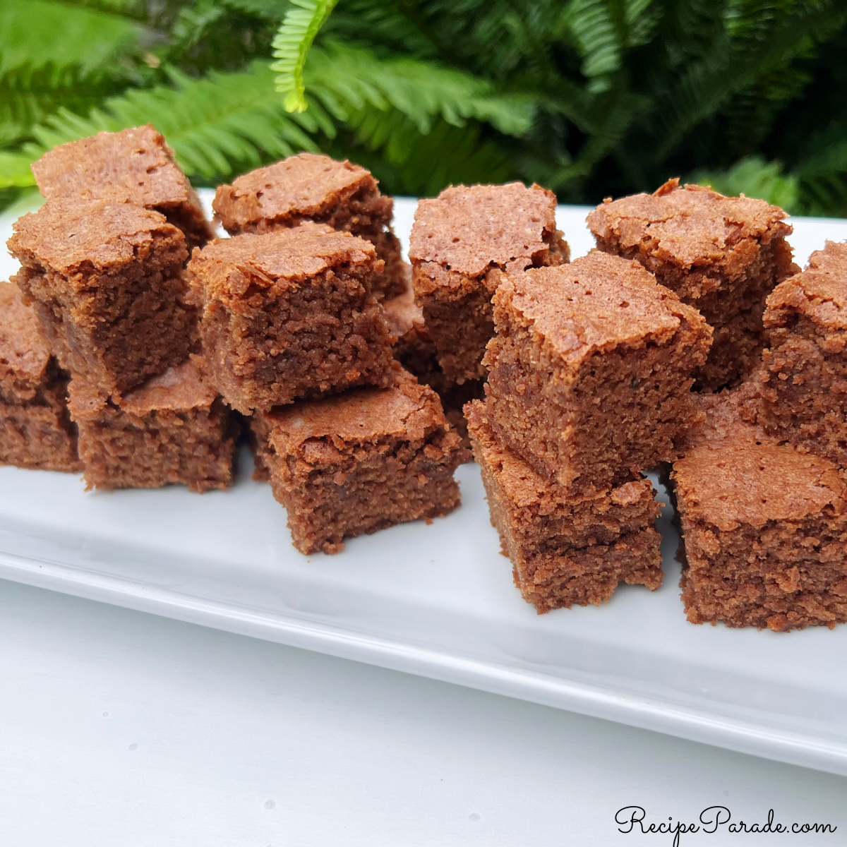 Homemade brownies stacked on a platter.
