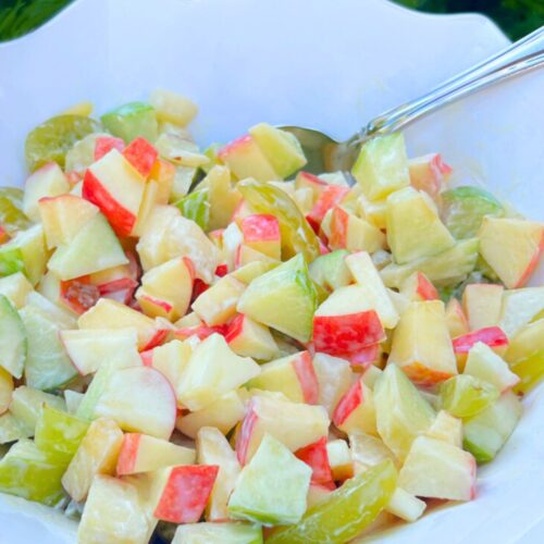 Colorful apple salad in a white bowl.
