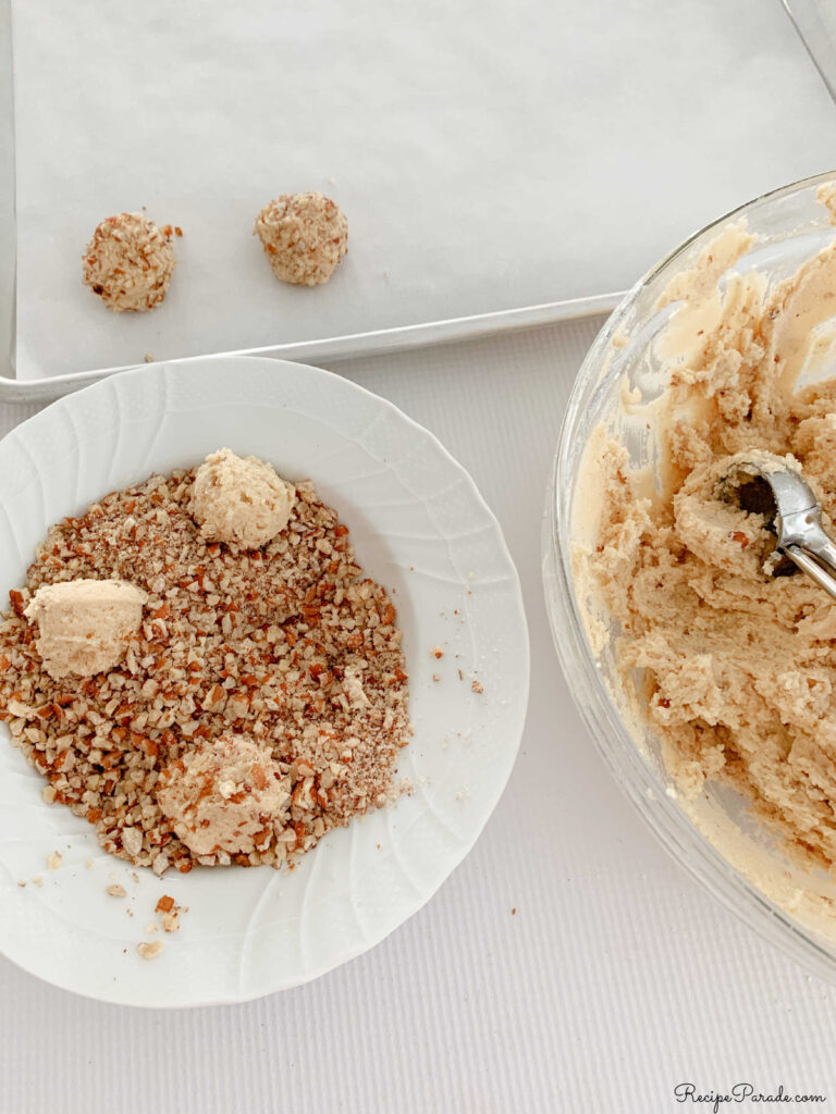 Scooping balls of cookie dough and rolling through toasted pecans.