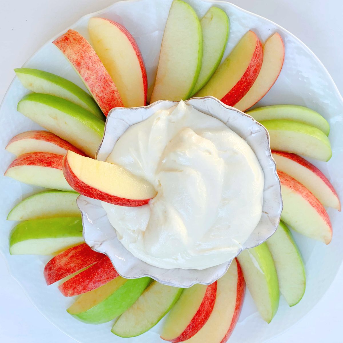 Sliced apples arranged around bowl of apple dip.