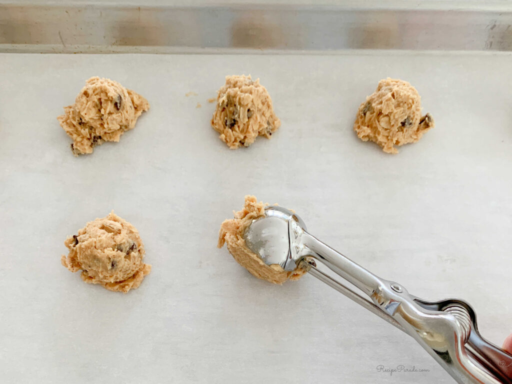 Adding scoops of cookie dough onto lined cookie sheet.