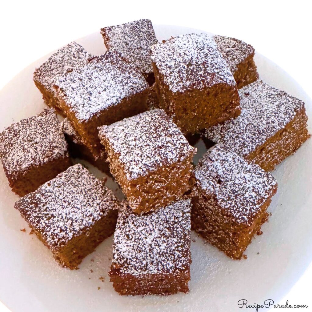 Platter of gingerbread squares, dusted with powdered sugar.