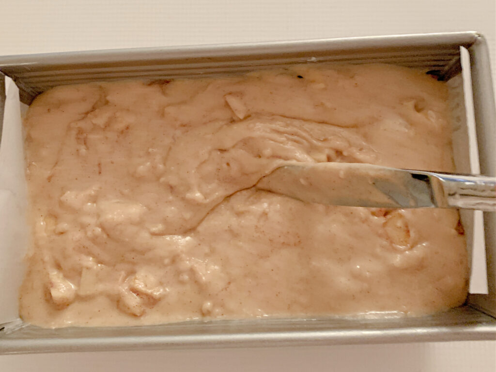 Loaf pan with apple bread batter.