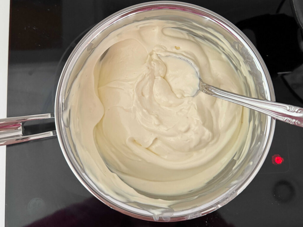 Combining cream cheese and sour cream in a saucepan over low heat.
