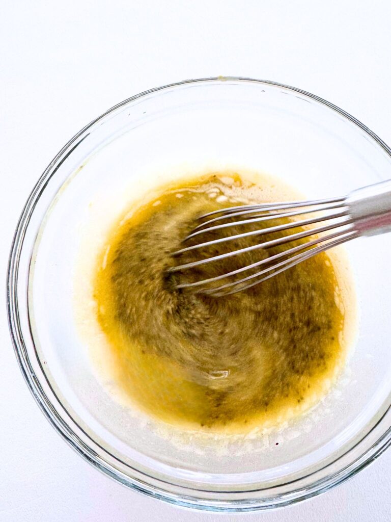 Bowl of butter and mustard mixture or ham and cheese sliders.