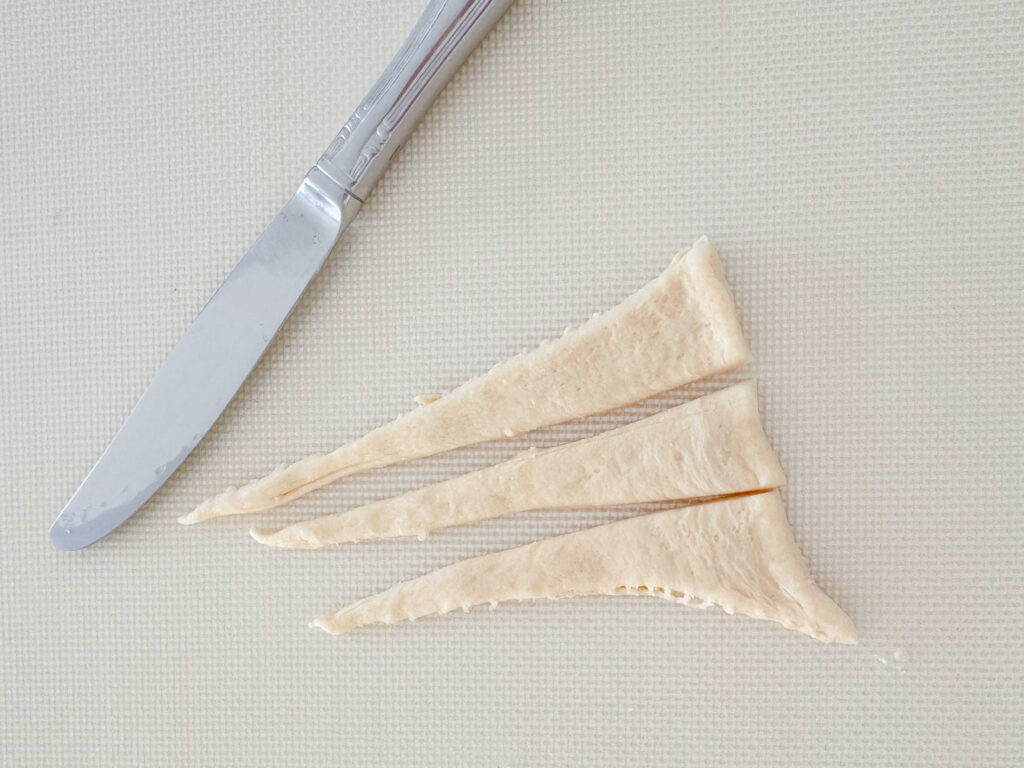 Cutting long, narrow triangles of crescent roll dough.