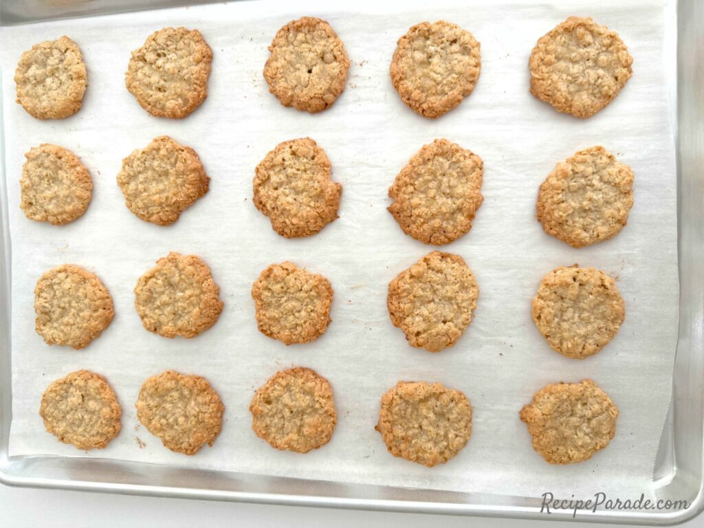 Crisp Oatmeal Cookies, freshly baked, on lined cookie sheet.