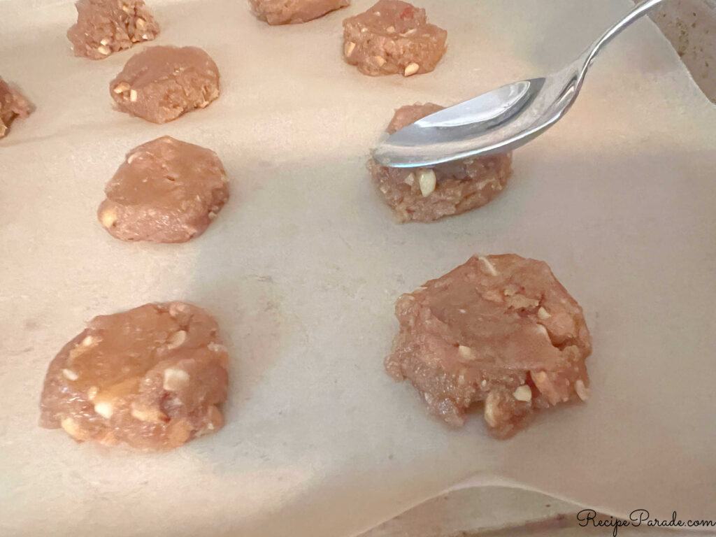 Lining up the mounds of cookie dough on a cookie sheet and lightly flattening with back of spoon.