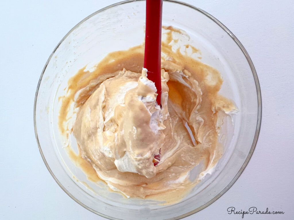 Folding cool whip into peanut butter pie.